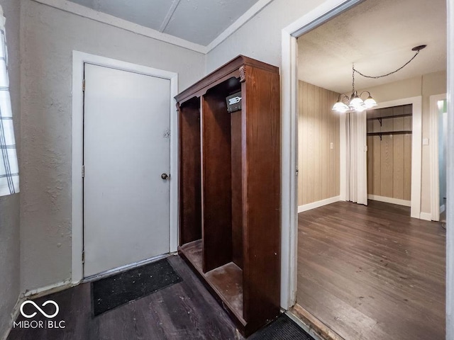 entryway with an inviting chandelier, dark hardwood / wood-style flooring, and wood walls