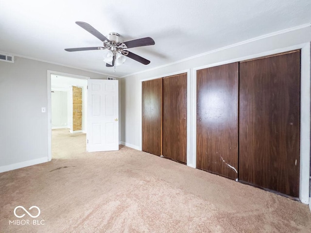 unfurnished bedroom with crown molding, light carpet, and two closets