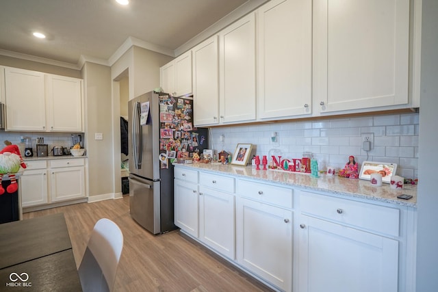 kitchen with white cabinets, stainless steel fridge, light wood-type flooring, and tasteful backsplash