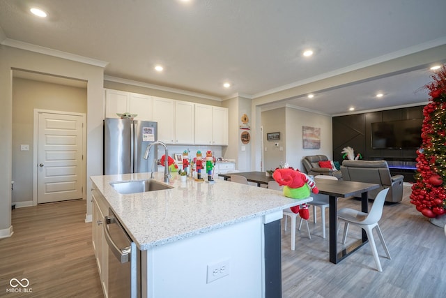 kitchen featuring appliances with stainless steel finishes, sink, white cabinetry, and an island with sink