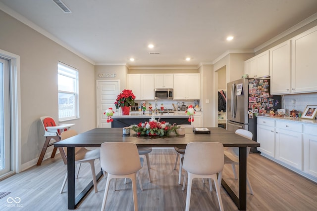 kitchen with backsplash, crown molding, light wood-type flooring, appliances with stainless steel finishes, and white cabinetry