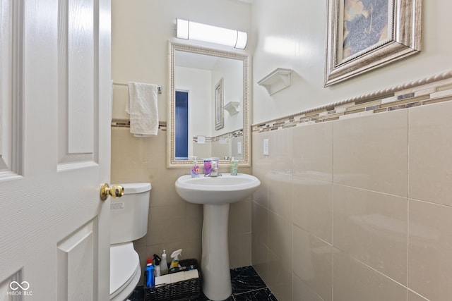 bathroom featuring sink, tile walls, and toilet