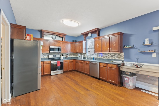 kitchen featuring decorative backsplash, sink, light hardwood / wood-style floors, and appliances with stainless steel finishes