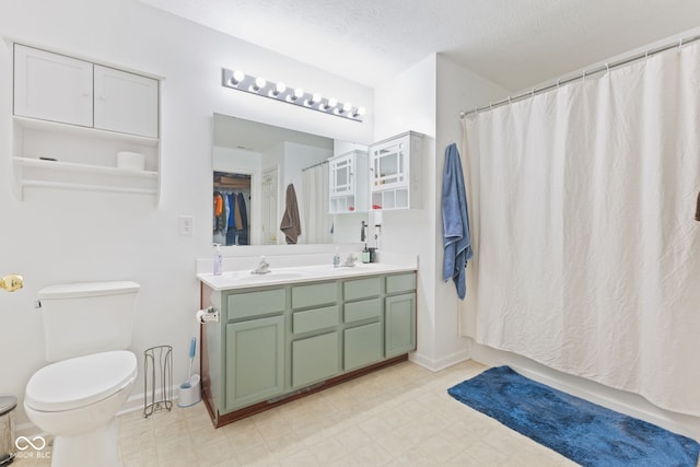 bathroom featuring a shower with shower curtain, vanity, toilet, and a textured ceiling