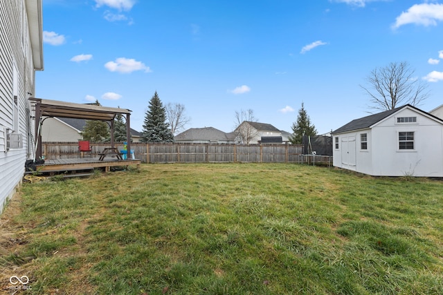 view of yard with a trampoline, an outdoor structure, and a deck