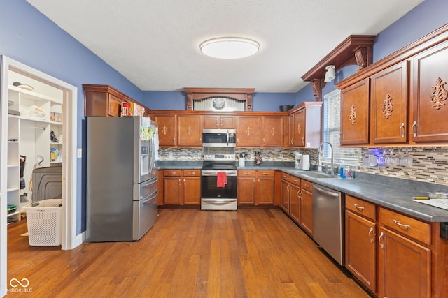 kitchen with dark hardwood / wood-style flooring, decorative backsplash, sink, and appliances with stainless steel finishes