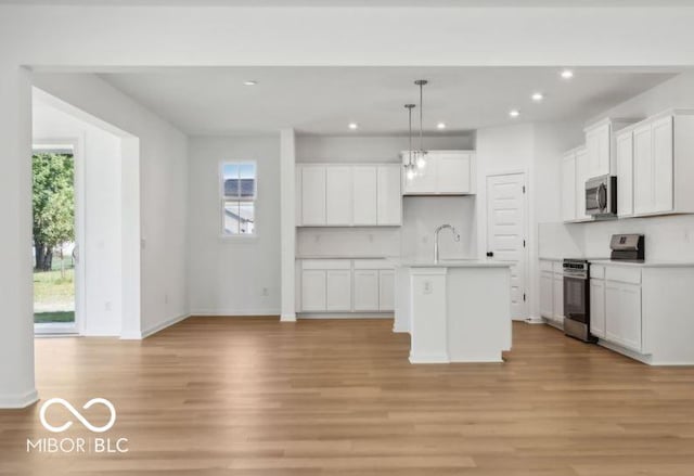 kitchen featuring a wealth of natural light, stainless steel appliances, and a kitchen island with sink