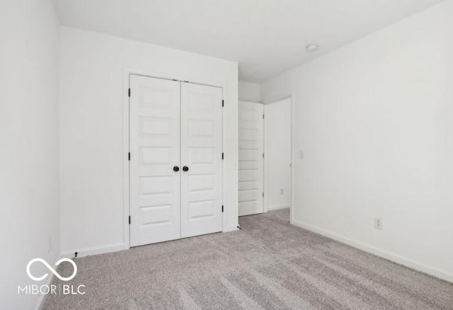 unfurnished bedroom featuring light carpet and a closet