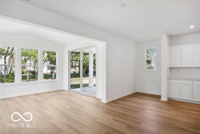 unfurnished dining area featuring light hardwood / wood-style floors and lofted ceiling