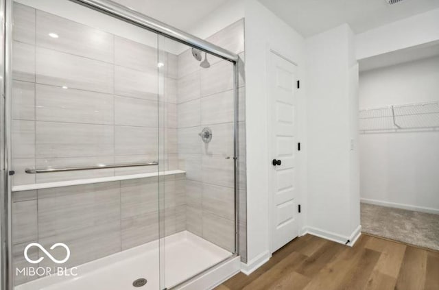 bathroom with hardwood / wood-style flooring and an enclosed shower