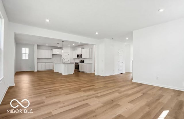 unfurnished living room featuring sink and light hardwood / wood-style floors