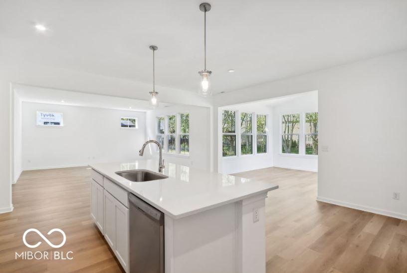 kitchen with light hardwood / wood-style flooring, stainless steel dishwasher, a kitchen island with sink, and sink