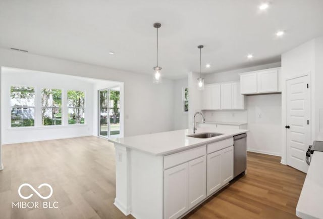 kitchen with sink, decorative light fixtures, white cabinetry, and an island with sink