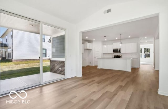 unfurnished living room with vaulted ceiling and light wood-type flooring