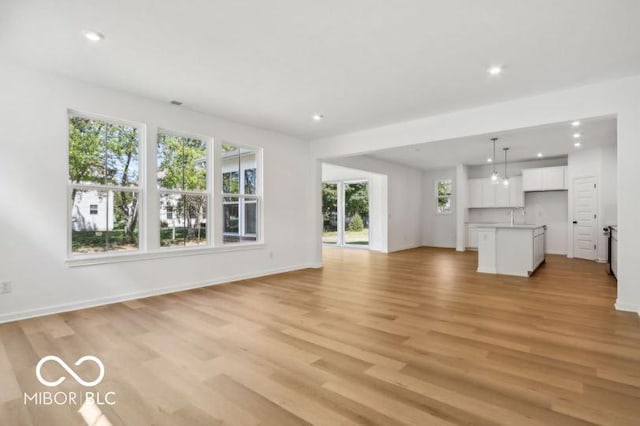 unfurnished living room featuring sink and light hardwood / wood-style floors