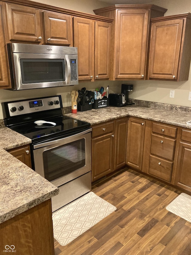 kitchen featuring dark hardwood / wood-style flooring, stainless steel appliances, and light stone counters