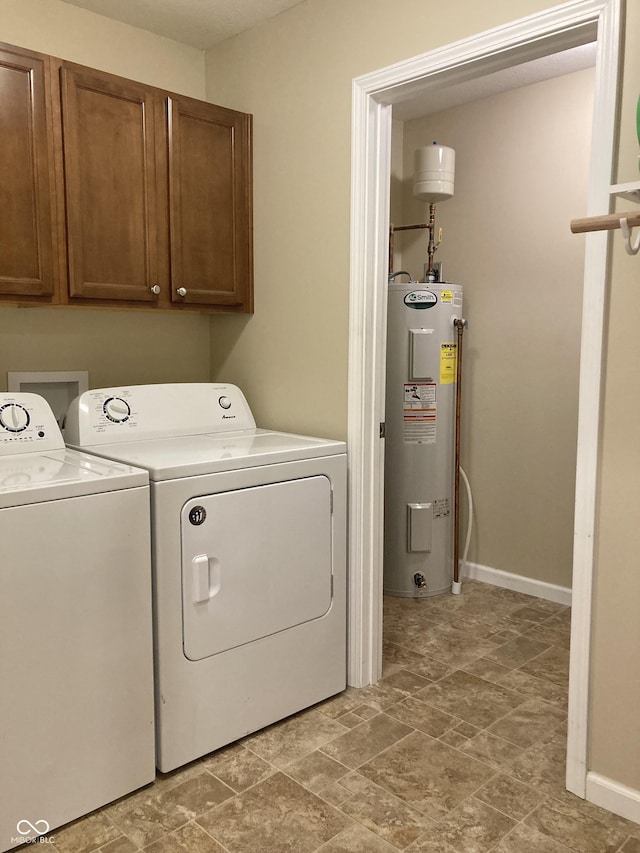 clothes washing area with water heater, washer and clothes dryer, and cabinets