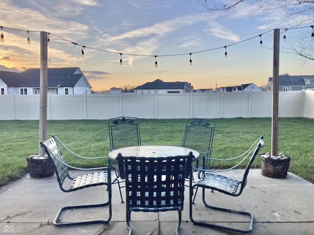 patio terrace at dusk featuring a yard