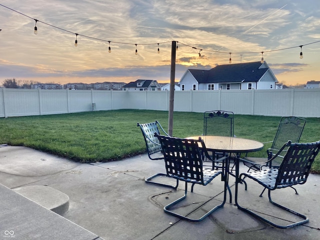 patio terrace at dusk featuring a yard