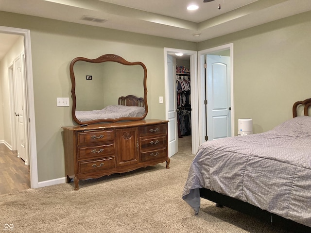 bedroom featuring a spacious closet, a closet, and light colored carpet