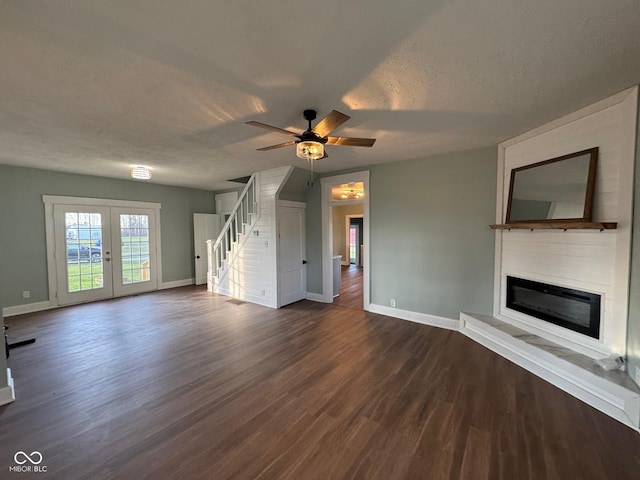 unfurnished living room featuring french doors, ceiling fan, dark hardwood / wood-style flooring, and a textured ceiling