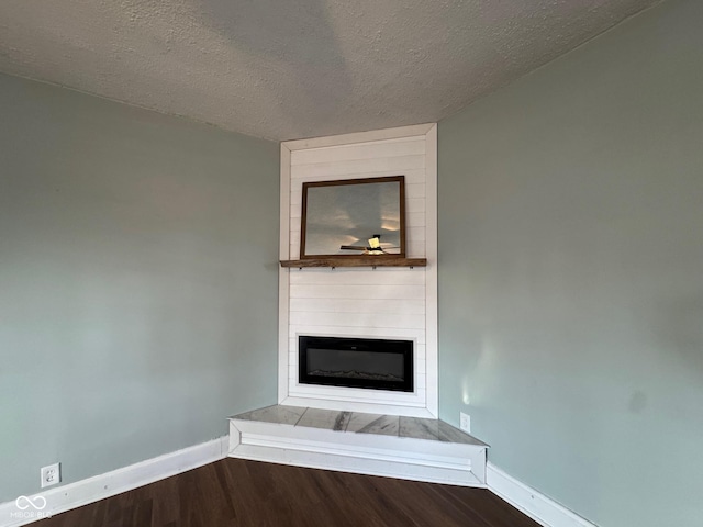 room details featuring ceiling fan, a large fireplace, hardwood / wood-style floors, and a textured ceiling