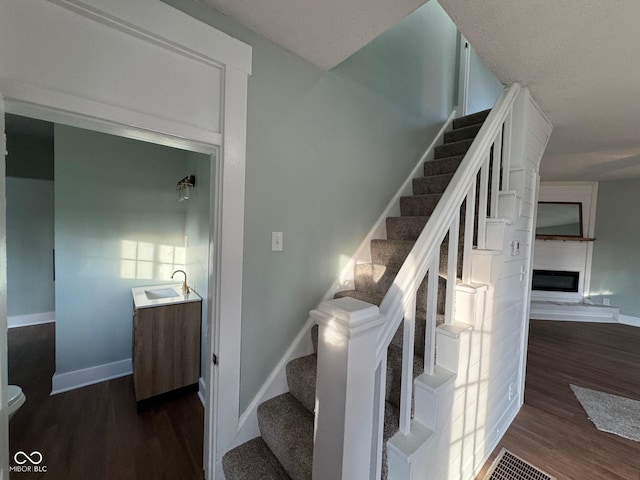 staircase with sink, a large fireplace, and hardwood / wood-style flooring