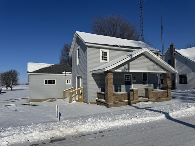 snow covered back of property with covered porch