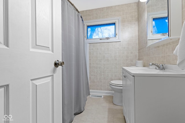 bathroom with a shower with curtain, vanity, tile walls, tile patterned flooring, and toilet