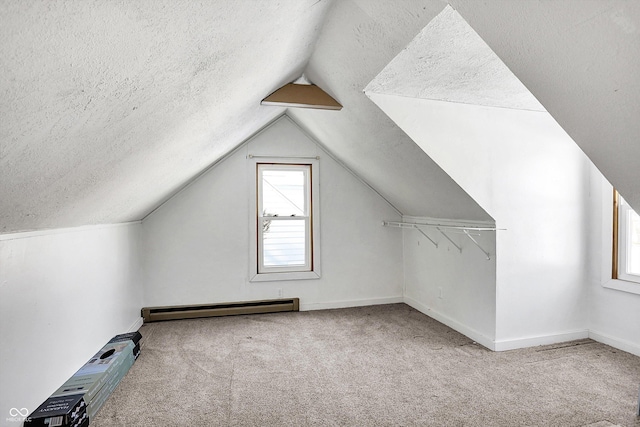 bonus room with baseboard heating, light colored carpet, vaulted ceiling, and a textured ceiling