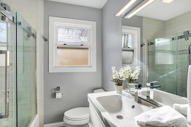 bathroom featuring toilet, a shower with shower door, and sink