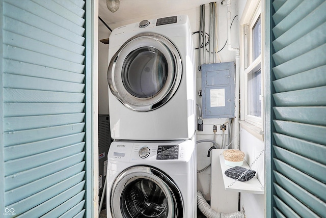 washroom featuring stacked washer and clothes dryer and electric panel