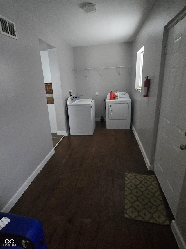 clothes washing area with dark hardwood / wood-style flooring and washing machine and clothes dryer