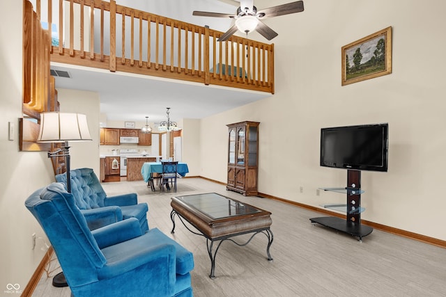 carpeted living room with a towering ceiling and ceiling fan with notable chandelier