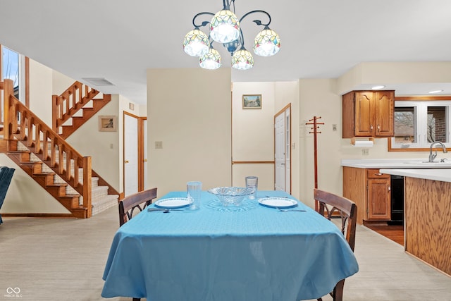 dining room featuring an inviting chandelier, sink, and light hardwood / wood-style flooring