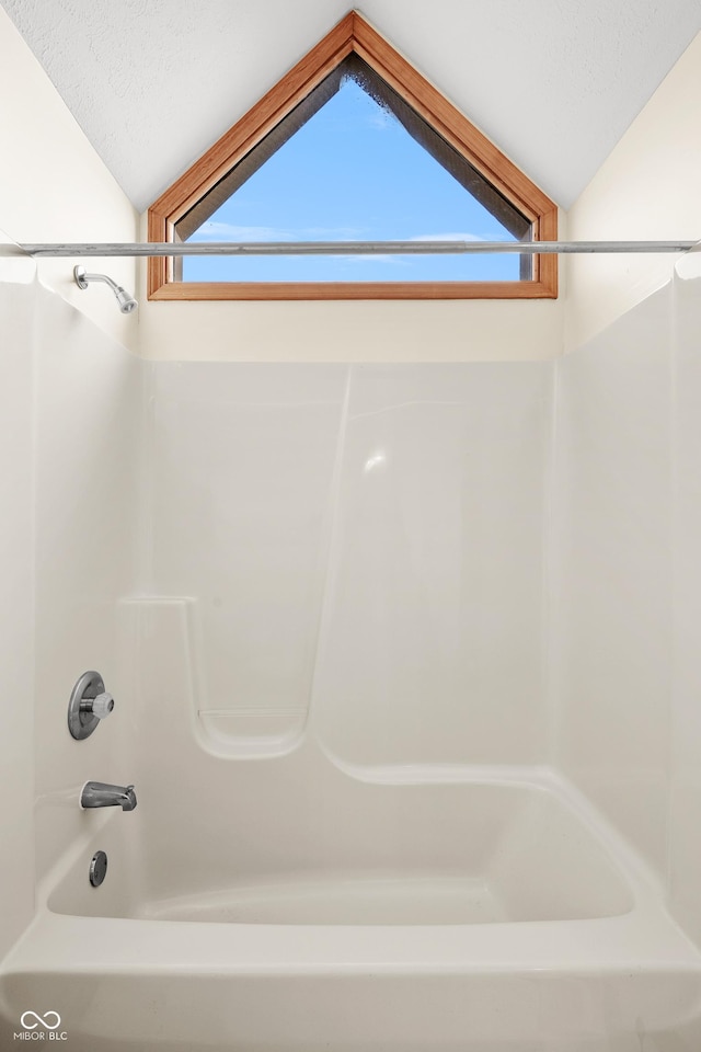 bathroom with plenty of natural light, tub / shower combination, and vaulted ceiling