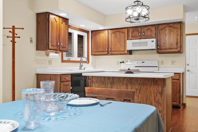 kitchen with dishwasher, sink, decorative light fixtures, hardwood / wood-style flooring, and range