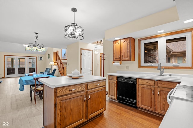 kitchen with pendant lighting, sink, black dishwasher, and light hardwood / wood-style flooring