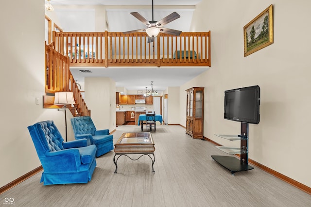 living room featuring ceiling fan with notable chandelier, light wood-type flooring, and high vaulted ceiling