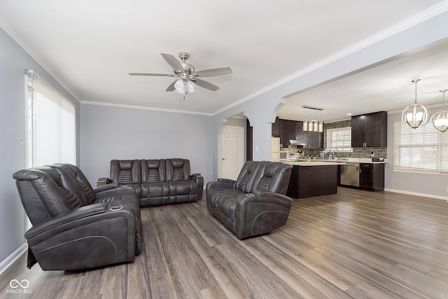 living room featuring crown molding, sink, ceiling fan with notable chandelier, and hardwood / wood-style flooring