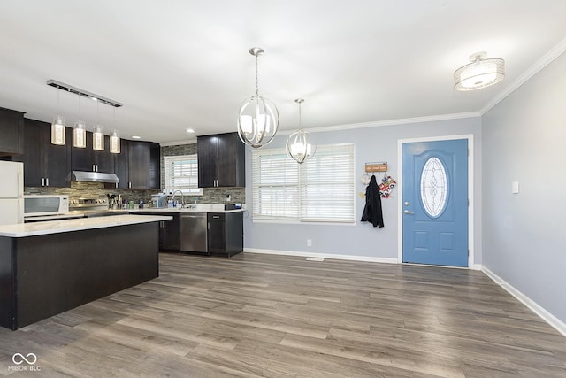 kitchen featuring backsplash, hanging light fixtures, light hardwood / wood-style flooring, ornamental molding, and appliances with stainless steel finishes