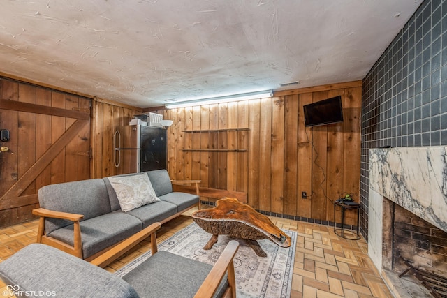 living room with wood walls, light parquet flooring, and tile walls