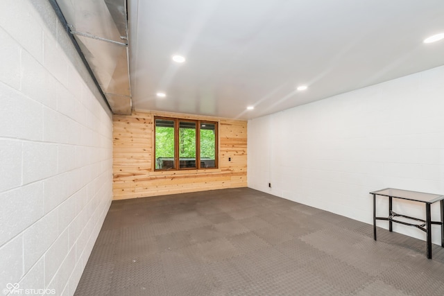 interior space featuring dark colored carpet and wooden walls