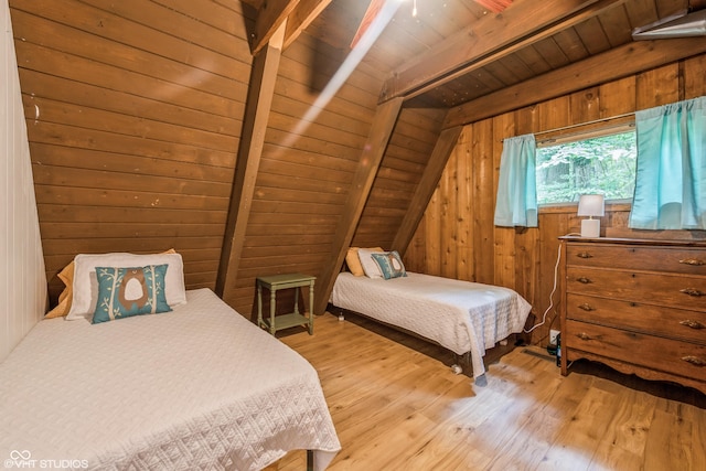 bedroom featuring vaulted ceiling with beams, light hardwood / wood-style floors, wooden ceiling, and wood walls