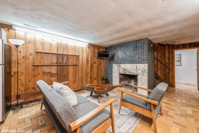 living room with a stone fireplace, wood walls, and parquet flooring