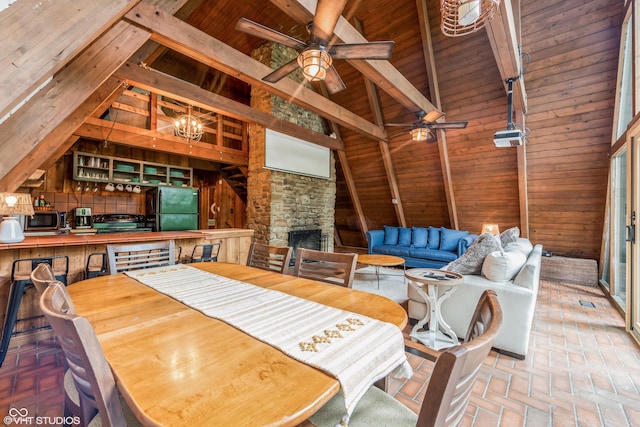 dining space featuring beamed ceiling, a stone fireplace, and wooden ceiling