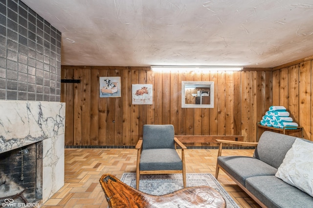 living room featuring parquet flooring, wooden walls, and a premium fireplace