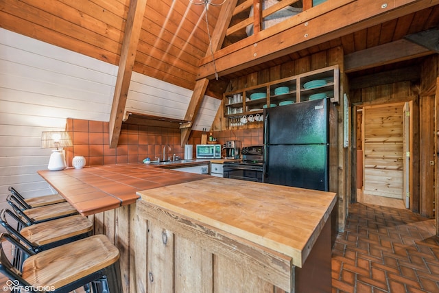 kitchen with sink, wooden ceiling, lofted ceiling, wooden walls, and black appliances