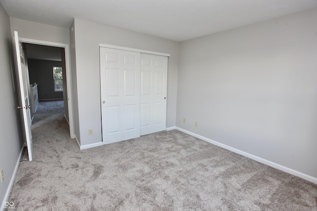 unfurnished bedroom featuring a closet and light colored carpet