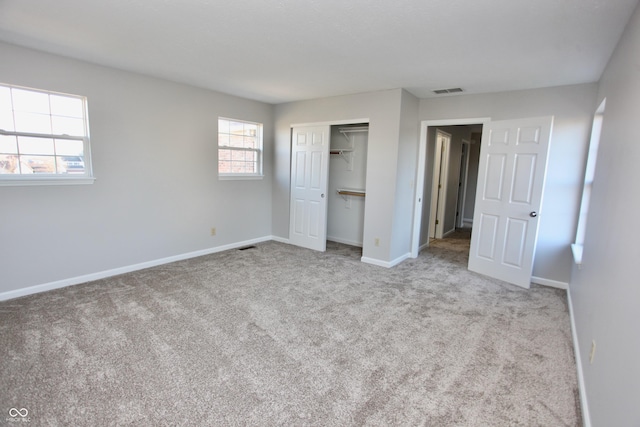 unfurnished bedroom with light colored carpet and a closet